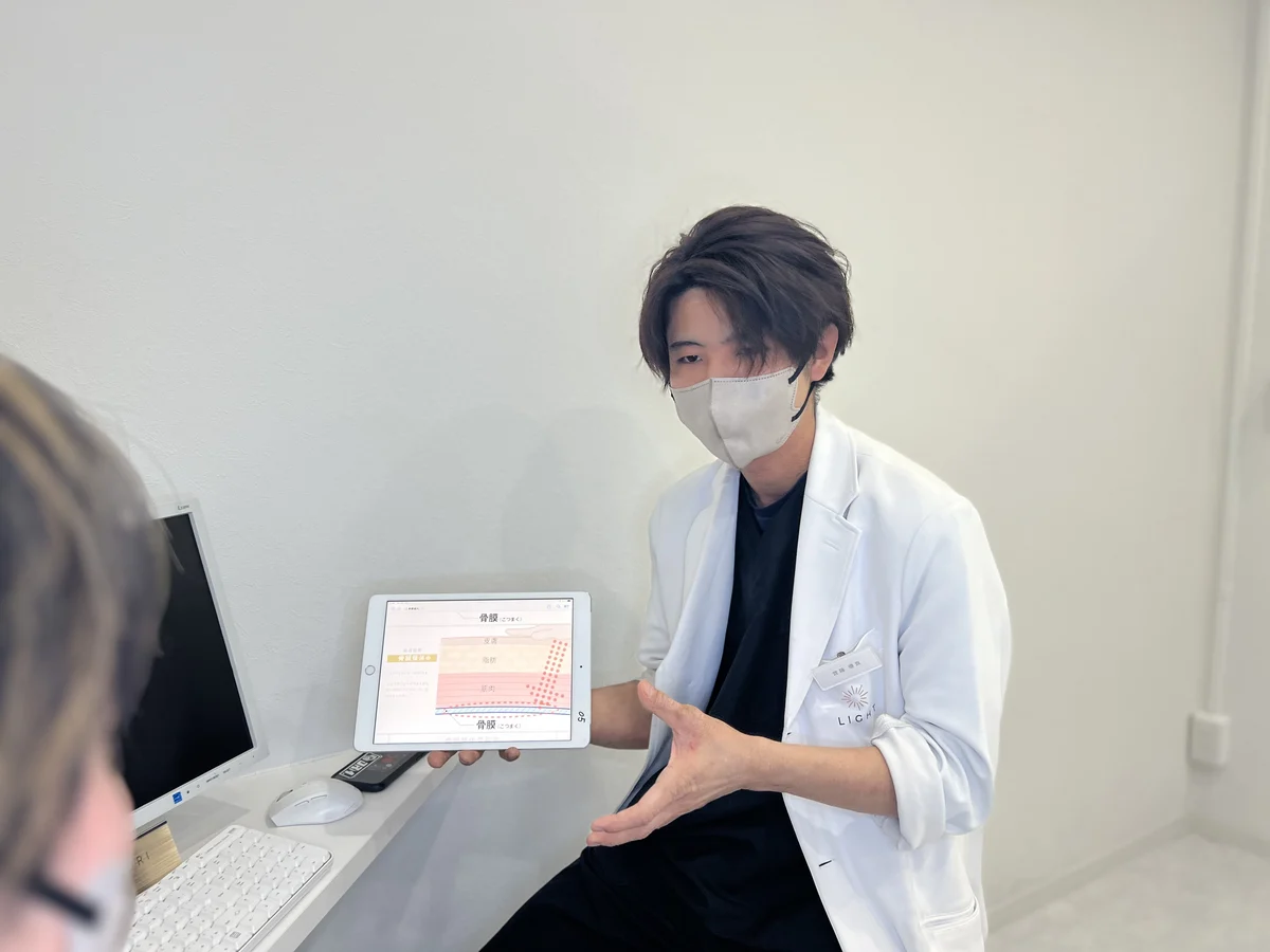 タブレットで身体の状態を説明する整体LIGHTスタッフ
