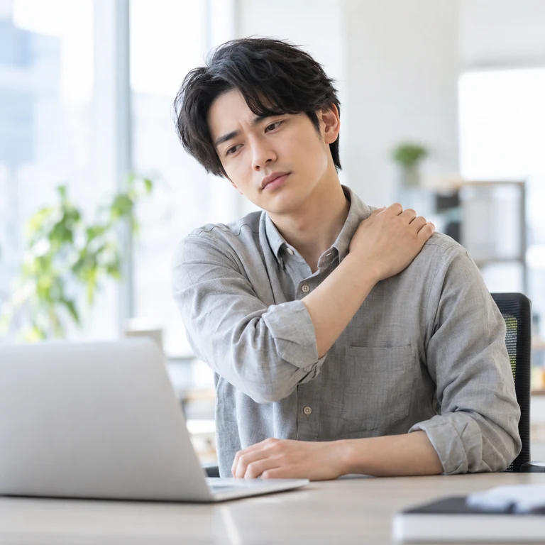 仕事が始まるとまた肩のつらさが気になる男性のAIイメージ画像
